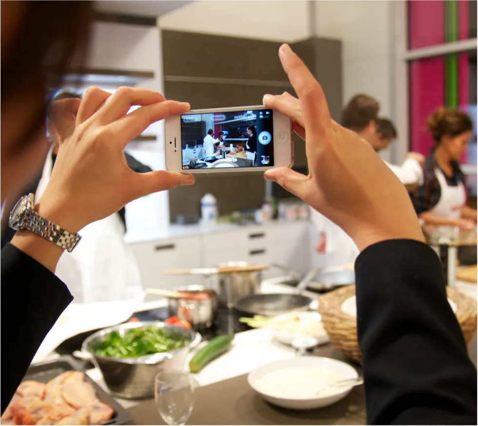 Frau macht Handybild von einem Kochevent