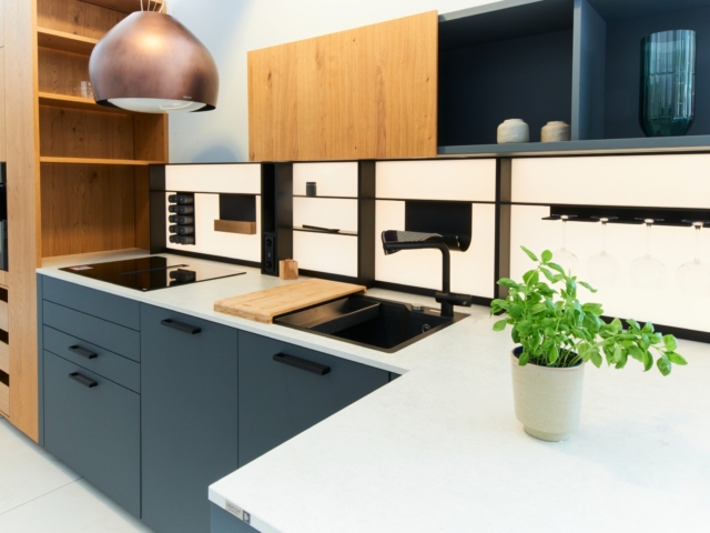 Küchenzeile mit dunkelblauer Front und einem beistehenden Schrank mit Holzfront