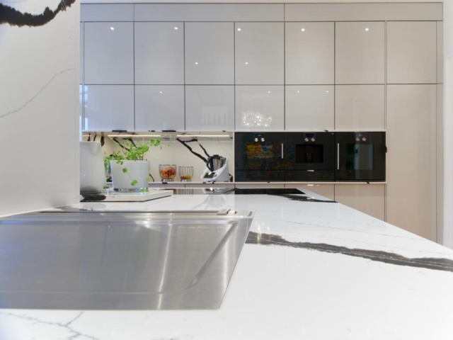 Küchenzeile mit geschlossener Hochglanzoptik und integrierter schwarzen Elektrogeräten
