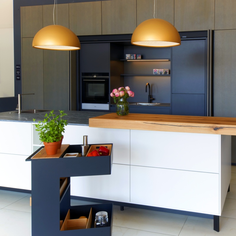 Moderne Küchenzeile mit weißer Front und einem blauen Servierwagen im Vordergrund