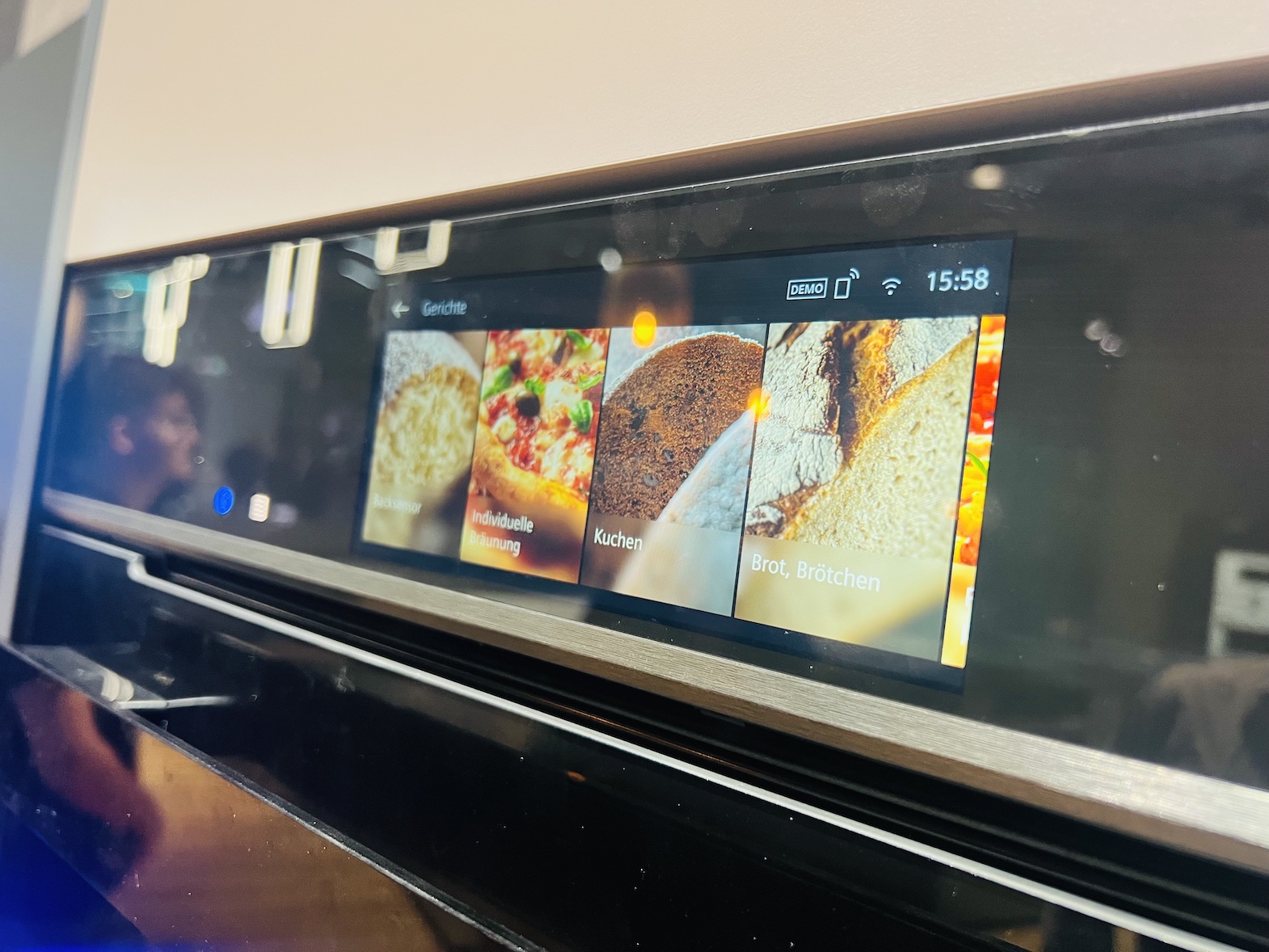 Smartes Bedienfeld eines Backofens mit Touchfeld, das Bilder von zubereiteten Speisen anzeigt