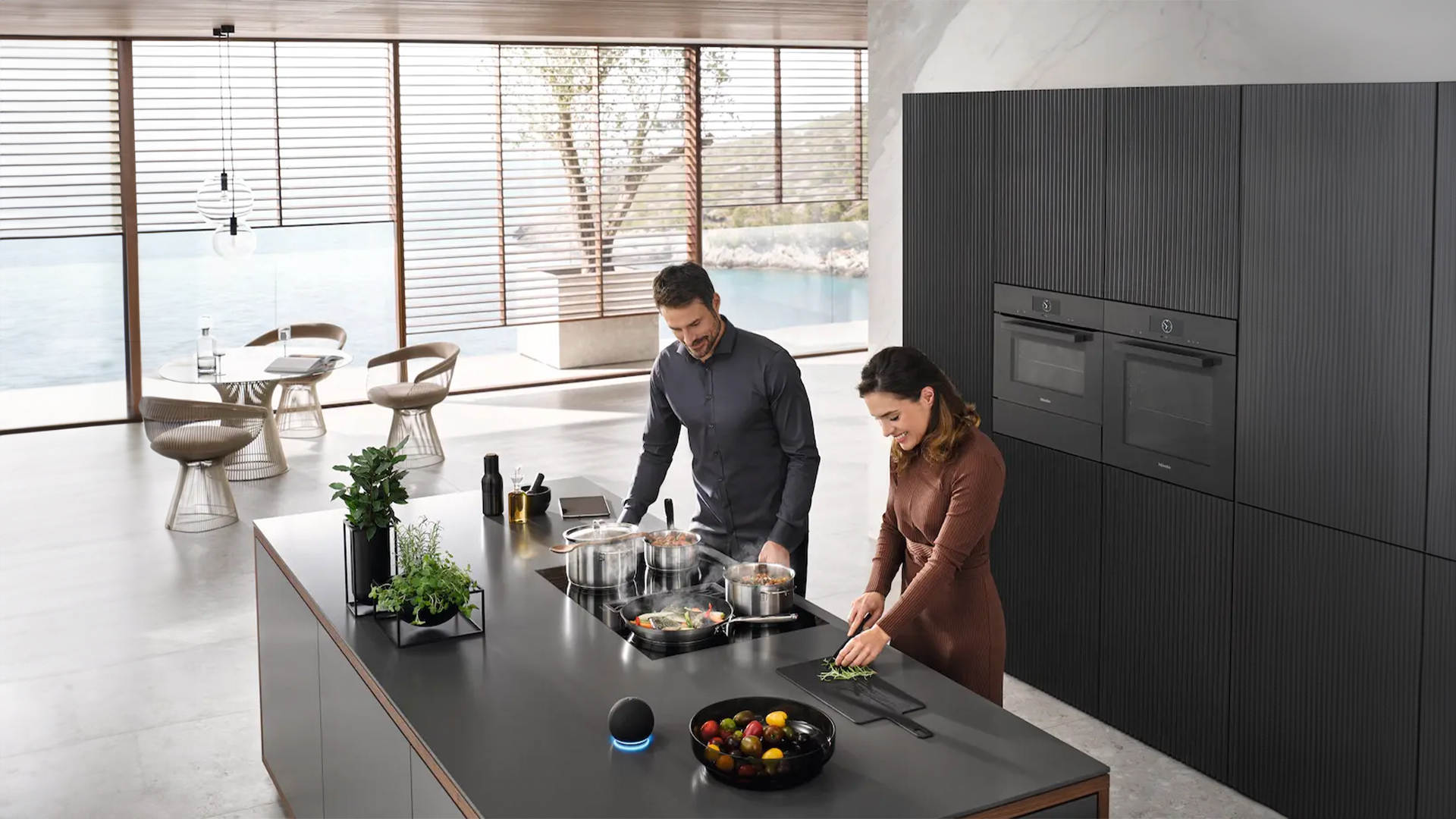Mann und Frau kochen in einer modernen Küche mit Miele Küchengeräten