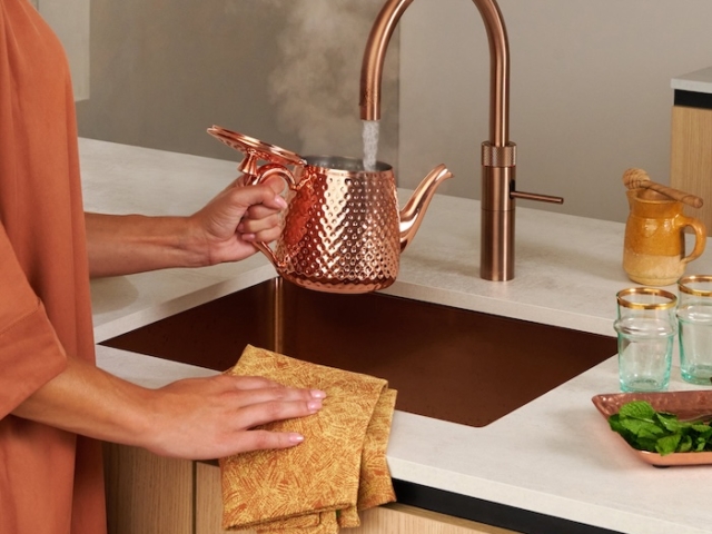 Frau gießt heißes Wasser aus einem Quooker Wasserhahn in eine Teekanne